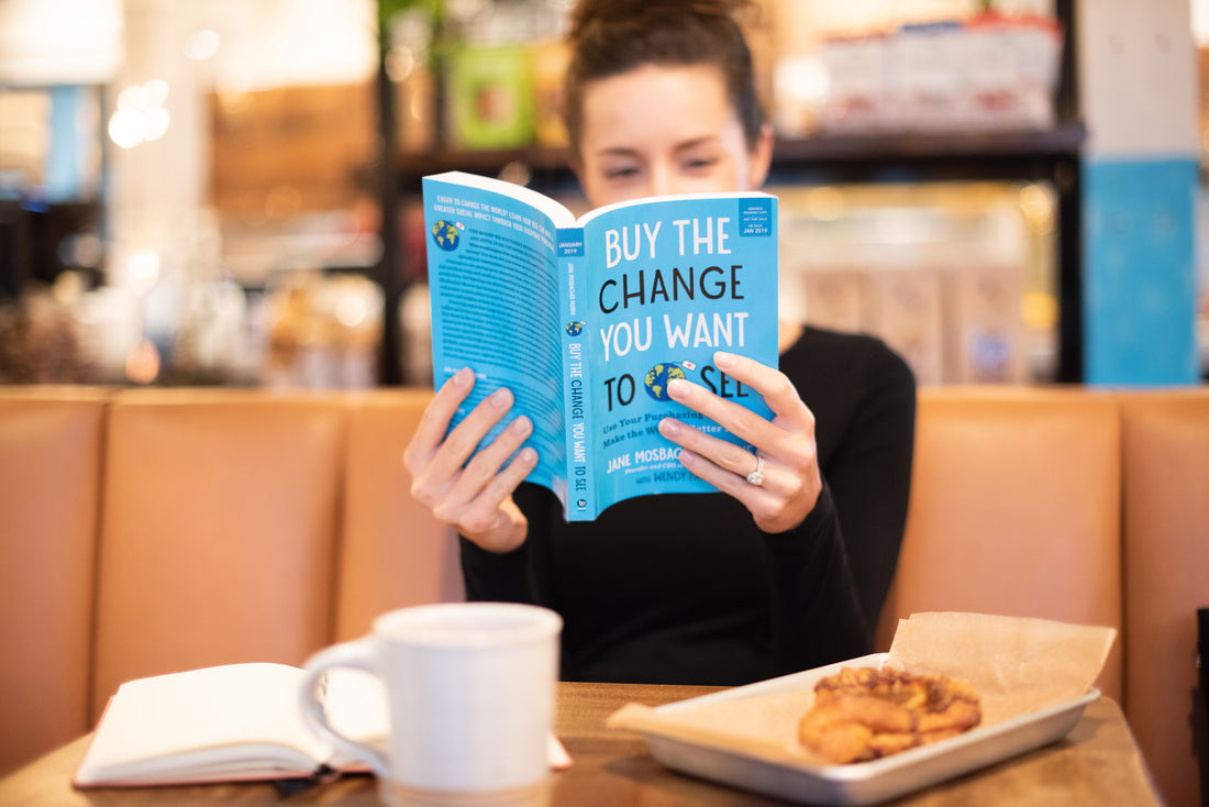 A woman reading "Buy the Change You Want to See" by Jane Mosbacher Morris