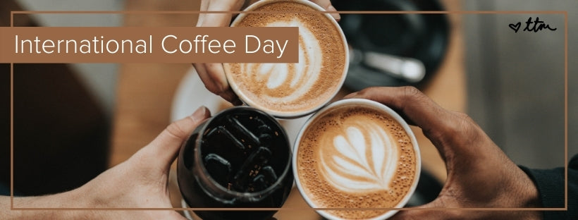 "International Coffee Day" with a close up of three cups of coffee with people holding them