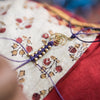 a close-up of a person's hand sewing a piece of fabric with purple thread