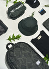 Flatlay of a backpack, bucket hat, t-shirt and dopp kit.  All in an olive leaf print.